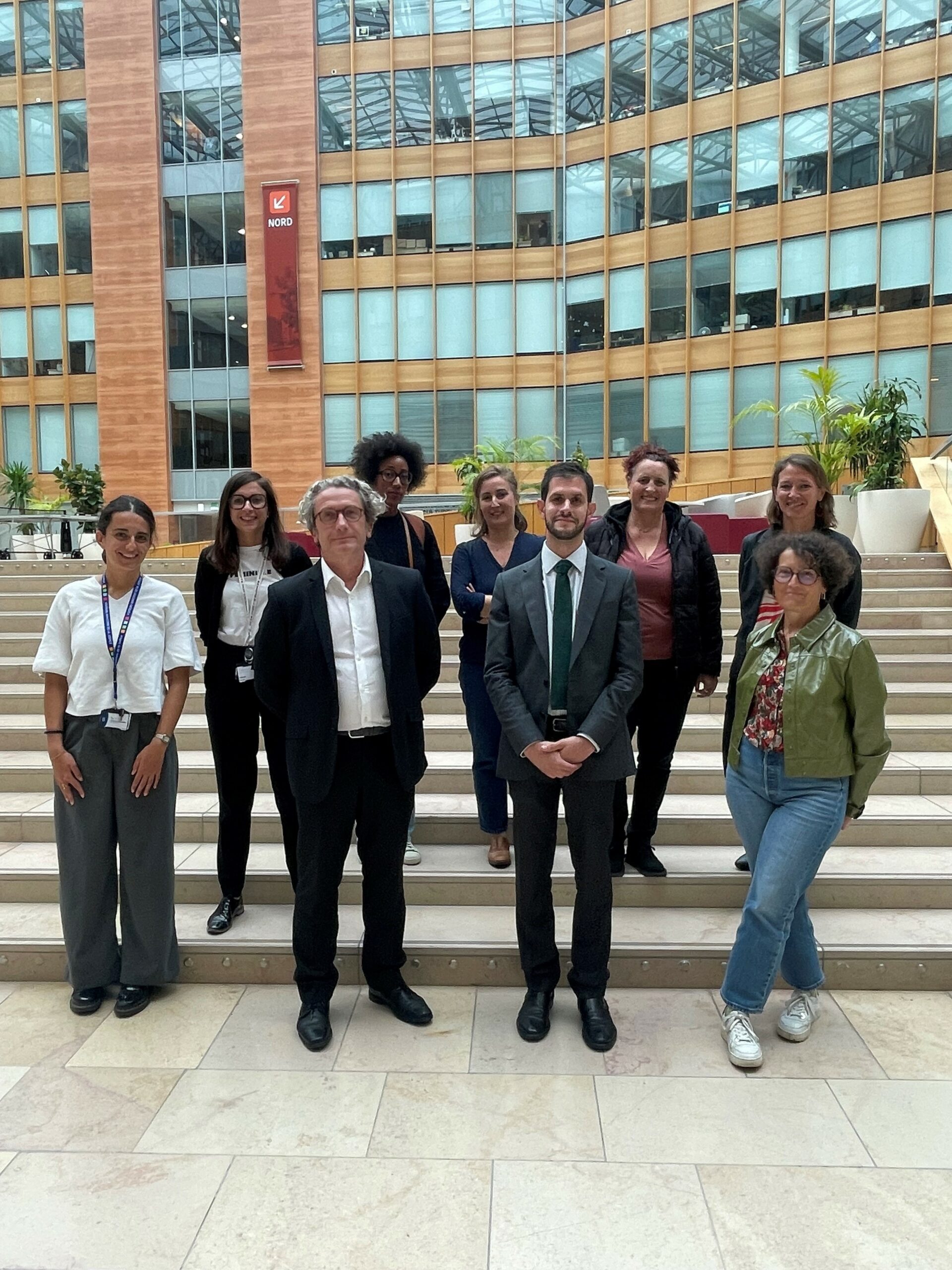 Photo de groupe du COEVAL devant les marches d'un bâtiment de 9 personnes